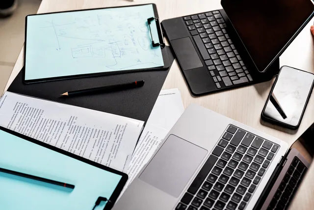 High-angle view of a modern workspace featuring laptops, tablet, clipboard, and documents. Ecommerce link building: UK targets and outreach