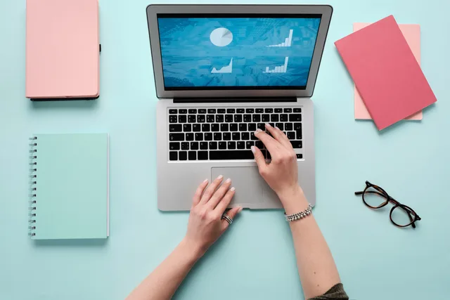 Hands typing on a laptop displaying data charts, with pink and teal office accessories. Ecommerce SEO best tools explained by the data sources they rely on