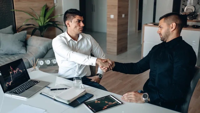 Two men shaking hands in an office, symbolizing successful agreement or partnership. Ecommerce SEO contracts: clauses to check before signing