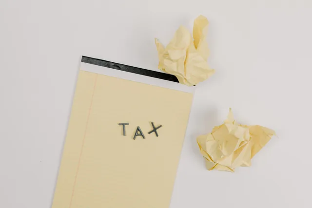 Flat lay of a notepad labeled 'tax' with crumpled paper on a white background, symbolizing financial stress. Ecommerce SEO costs: official UK VAT and ICO figures